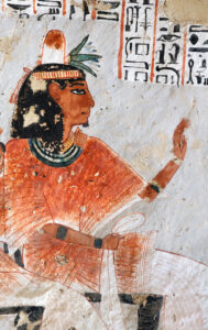 Roy seated, his wig is topped by a perfume cone and a lotus flower. 